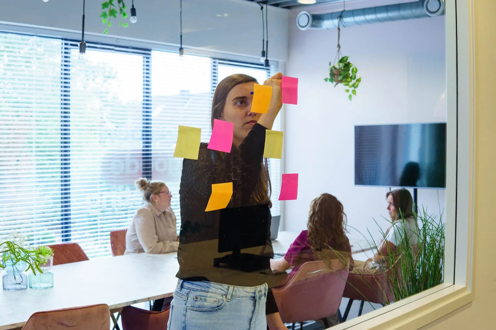 Doelen op post-its tegen de glazen wand tijdens een sessie bij BURO210