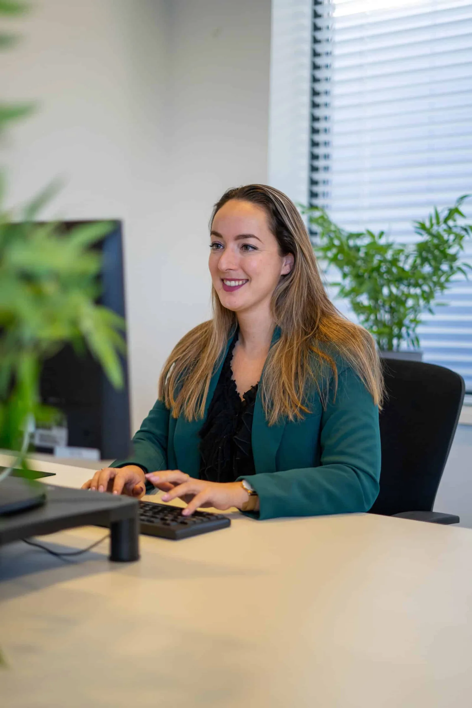 Collega in een groene blazer werkt achter haar computer