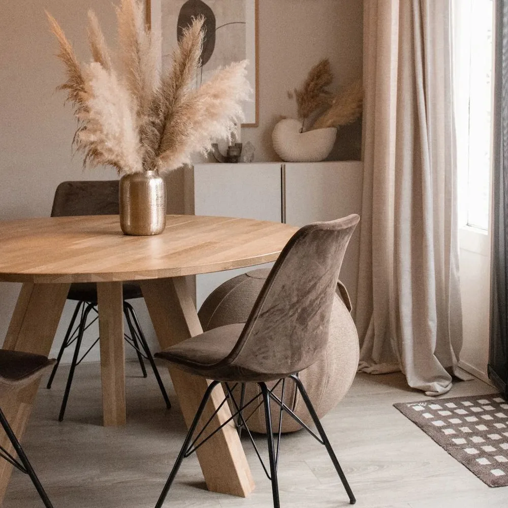 Eethoek van Kick Collection met houten tafel, bruine stoelen en een vaas pampasgras